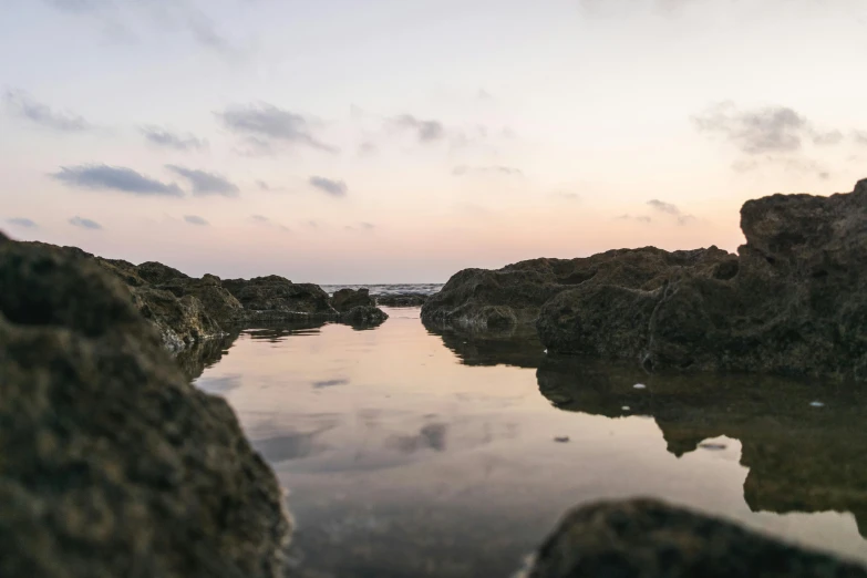 a body of water sitting on top of a rocky beach, a picture, unsplash, calm evening, rock pools, big island, low angle photo