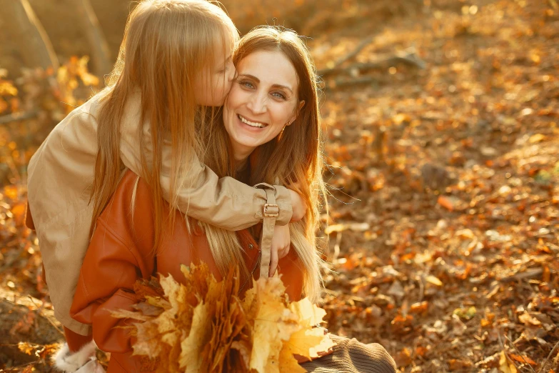 a couple of women sitting on top of a pile of leaves, pexels, sweet hugs, mom, thumbnail, brown