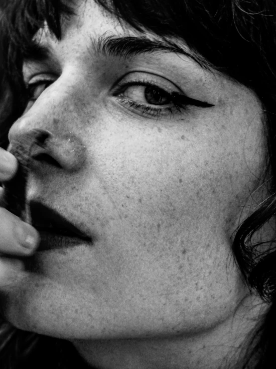 a black and white photo of a woman smoking a cigarette, a black and white photo, by Lucia Peka, unsplash, photorealism, freckles!!!, close up 1 9 9 0, jack white, by tom purvis