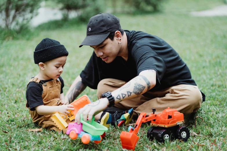 a man playing with a child in the grass, a cartoon, pexels contest winner, tattooed, kids toys, worksafe. instagram photo, asian man