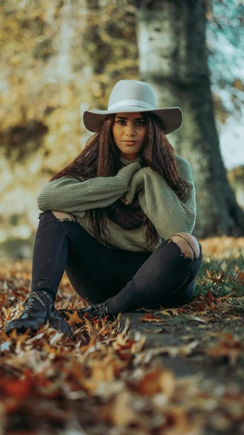 a woman sitting on the ground wearing a hat, inspired by Elsa Bleda, pexels contest winner, foliage clothing, low quality photo, australian, wearing boots