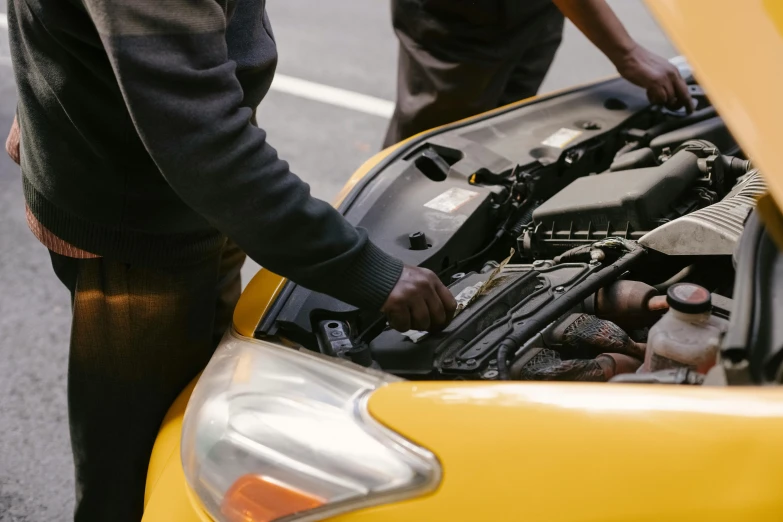 two men looking under the hood of a yellow car, pexels contest winner, detail and care, avatar image, broken down, high resolution image