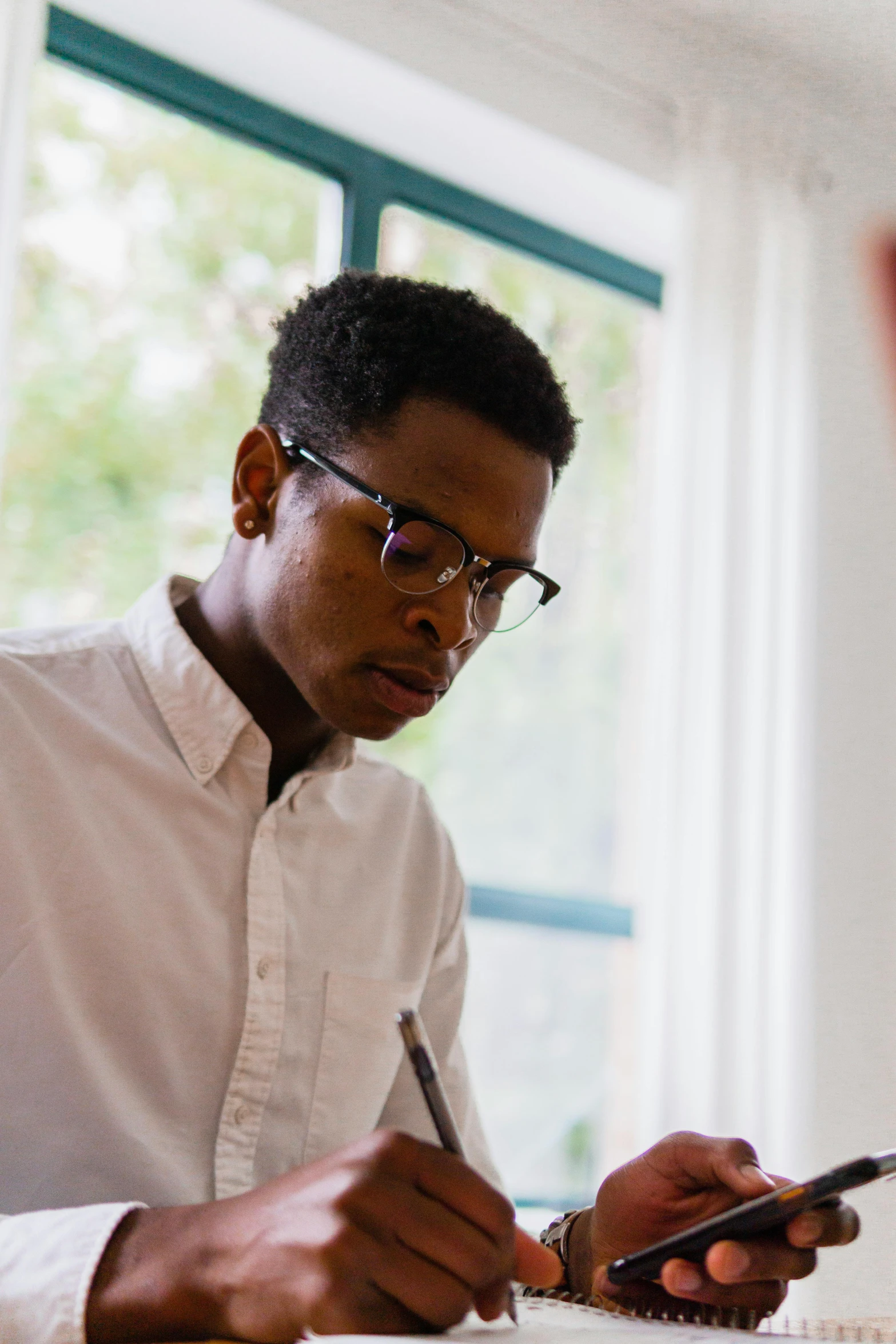 a man sitting at a desk using a cell phone, pexels contest winner, academic art, wearing a white button up shirt, young thug, square rimmed glasses, profile image