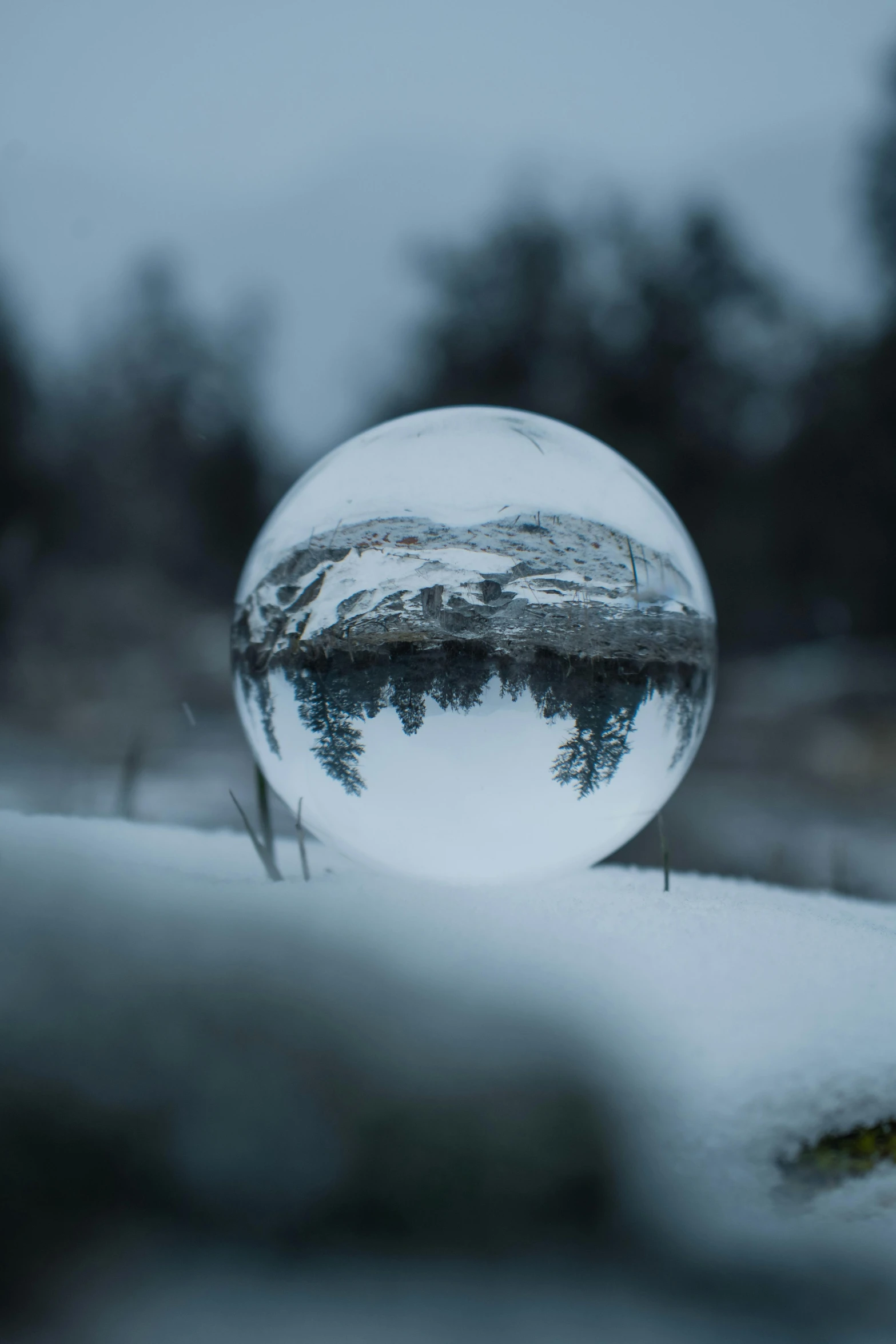 a glass ball sitting on top of a snow covered ground