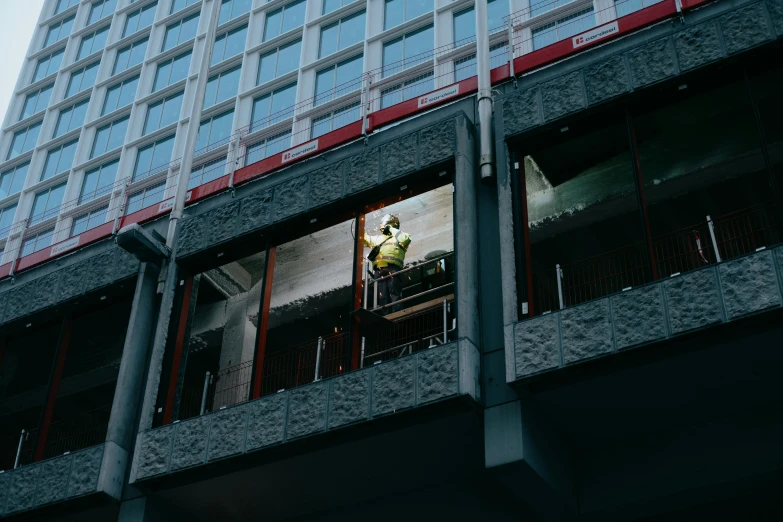 a man standing on top of a balcony next to a tall building, under repairs, unsplash photography, the windows are lit, koji morimoto shinjuku