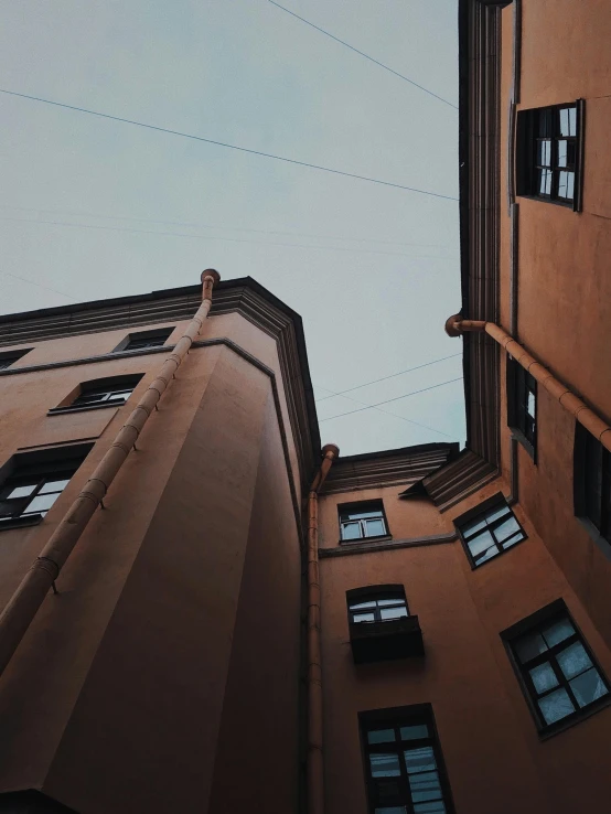 a couple of tall buildings next to each other, a photo, pexels contest winner, alleys, head looking up, swedish houses, beige and dark atmosphere