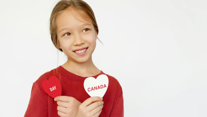 a little girl holding a paper heart with canada written on it, pexels contest winner, red flags holiday, product introduction photo, teaser, small