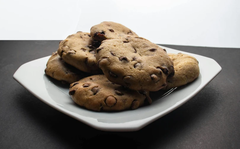 a plate of chocolate chip cookies on a table, a portrait, inspired by Gillis Rombouts, unsplash, renaissance, background image, 3/4 front view, various posed, 6 pack