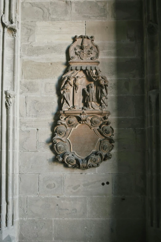 a stone wall mounted to the side of a building, a statue, by Barthélemy d'Eyck, unsplash, romanesque, decoration around the room, cartouche, inside cathedral, signed