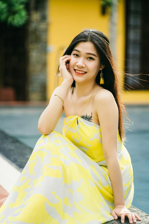 a woman in a yellow dress sitting on a ledge, inspired by Xie Sun, pexels contest winner, happily smiling at the camera, in style of lam manh, square, 1 8 yo