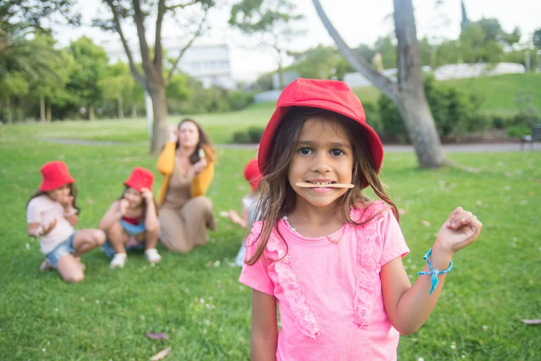 a little girl with a toothbrush in her mouth, a picture, inspired by The Family Circus, pexels contest winner, of a family standing in a park, wearing a silly hat, sydney park, aboriginal capirote