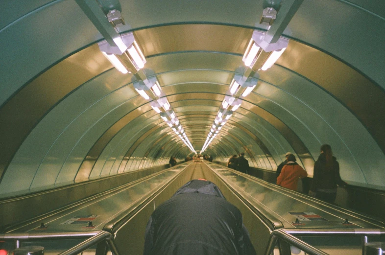 a group of people riding down an escalator, an album cover, unsplash, hyperrealism, underground tunnel, frank moth, in 2 0 0 2, low fi