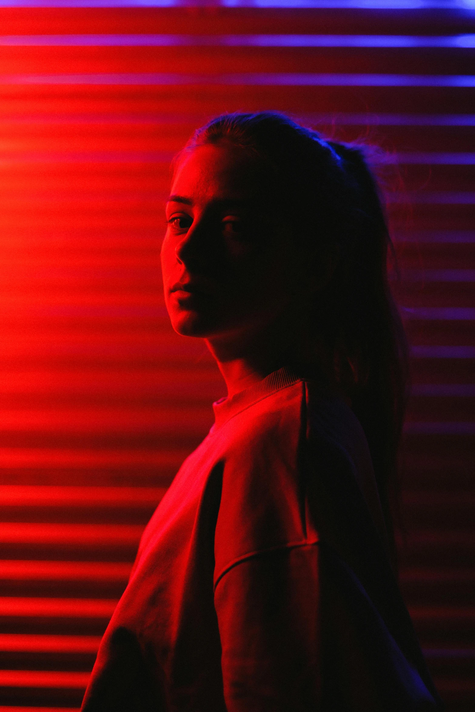 a woman standing in front of a red and blue light, pexels contest winner, teenage girl, portrait sophie mudd, reds, somber lighting