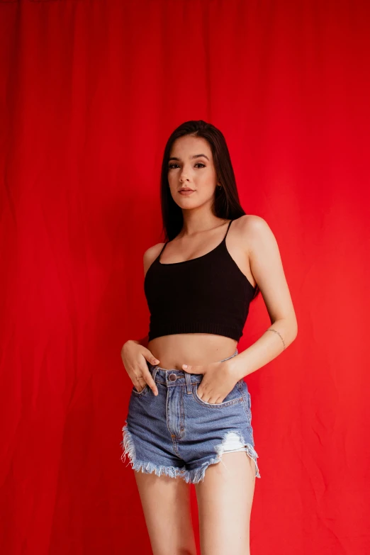 a woman standing in front of a red curtain, by Robbie Trevino, trending on pexels, realism, wearing a black cropped tank top, modeling shoot, malaysian, woman in streetwear