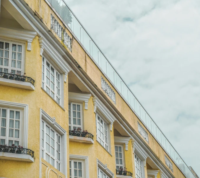 a yellow building with lots of windows and balconies, by Carey Morris, pexels contest winner, neoclassicism, hotel room, faded colors, view from ground, nazare (portugal)