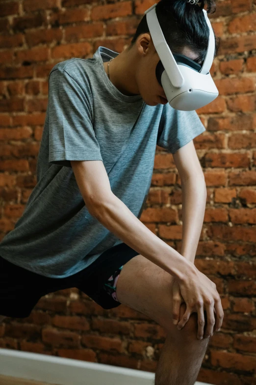 a man sitting on a skateboard in front of a brick wall, trending on pexels, renaissance, wrestlers wearing vr headsets, oculus quest 2, hunched shoulders, in a gym