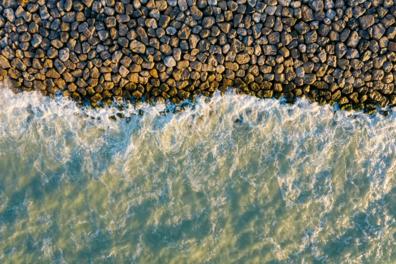 a person riding a surfboard on top of a body of water, pexels contest winner, realism, significant pebbles boundaries, seen from above, near a jetty, northern france