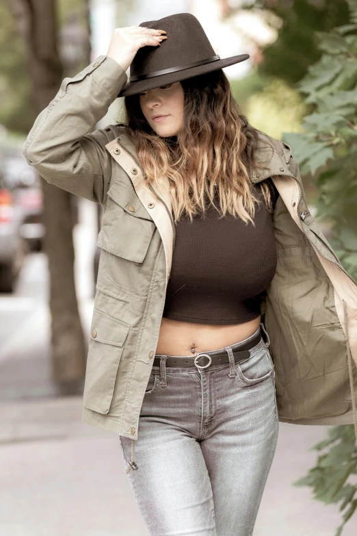 a woman walking down a street wearing a hat, a colorized photo, trending on pexels, figuration libre, wearing a sexy cropped top, action shot girl in parka, her belly button is exposed, wearing jeans and a black hoodie