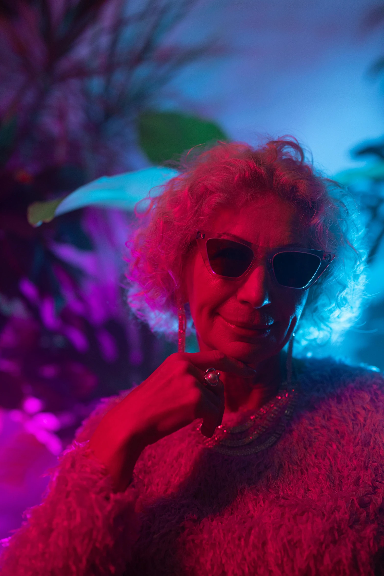 a close up of a person wearing sunglasses and a sweater, an album cover, inspired by Elsa Bleda, elderly woman, neon colored haze, tropics, flashing lights