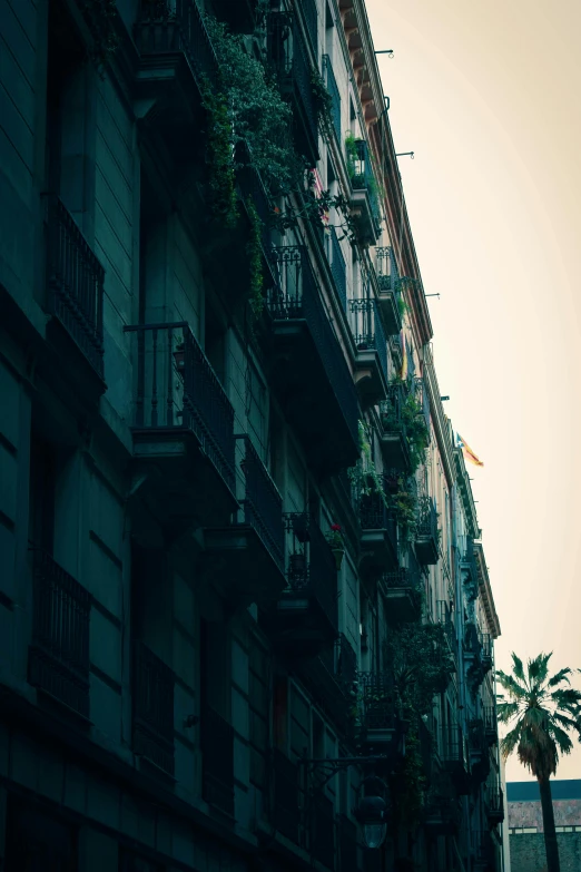 a tall building with balconies on the balconies, inspired by Elsa Bleda, unsplash contest winner, baroque, gothic quarter, distant photo, a green, early evening