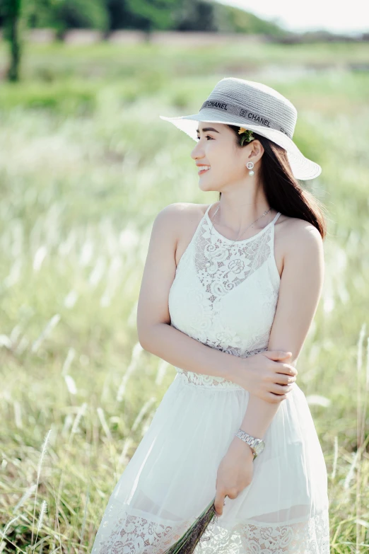 a woman in a white dress and hat standing in a field, by Ai-Mitsu, pexels contest winner, beautiful young asian woman, sleeveless, lacey accessories, in front of white back drop