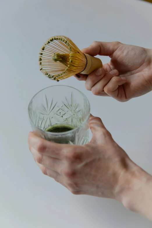 a person holding a whisk in their hand, inspired by Kanō Shōsenin, with clear glass, a green, concentrated, mini