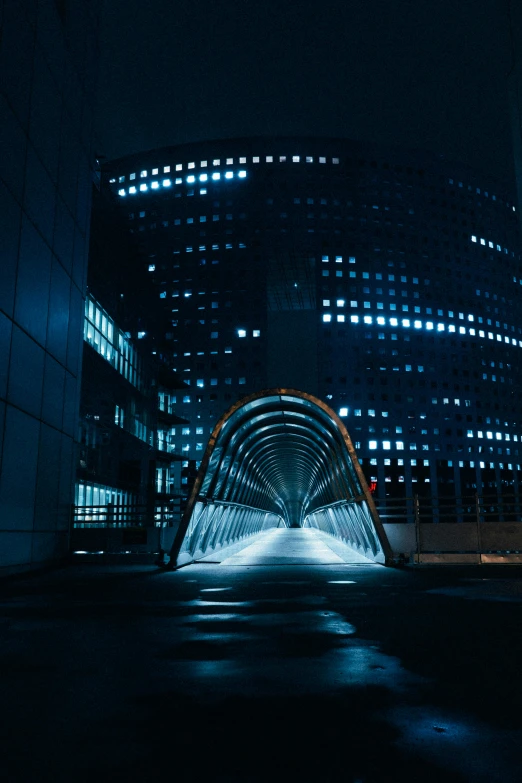 a tunnel in the middle of a city at night, pexels contest winner, light and space, in neotokyo, archs, cold blue lighting, dramatic buildings