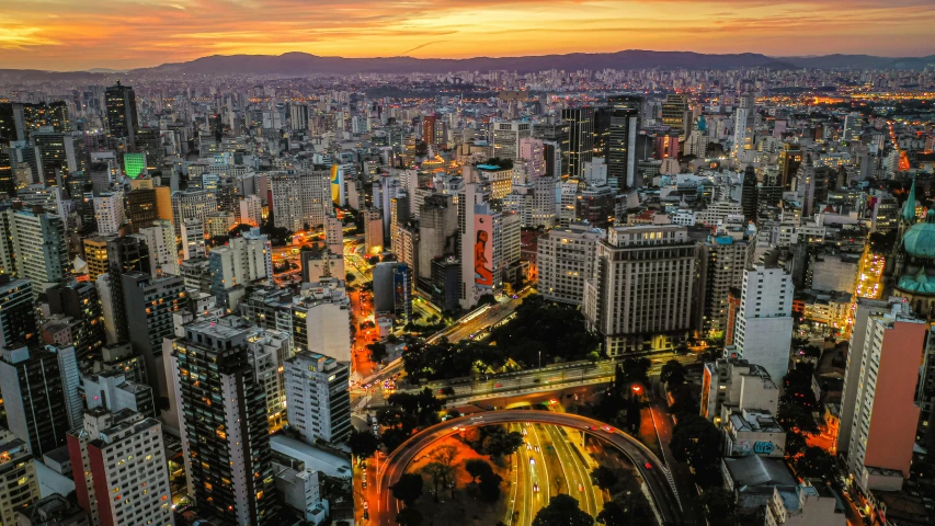 an aerial view of a city at night, by Luis Miranda, pexels contest winner, sunset photo at golden hour, avenida paulista, paradise in the background, youtube thumbnail