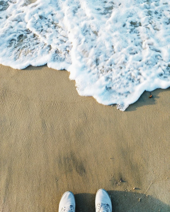 a person standing on a beach next to the ocean, from above, foamy waves, on a canva, thumbnail