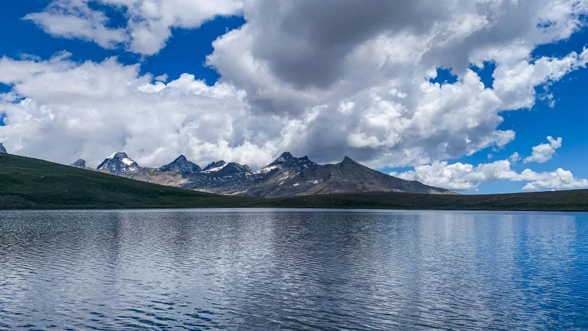 a large body of water with mountains in the background, by Muggur, pexels contest winner, hurufiyya, mountain lakes, with clouds in the sky, 2000s photo, fan favorite