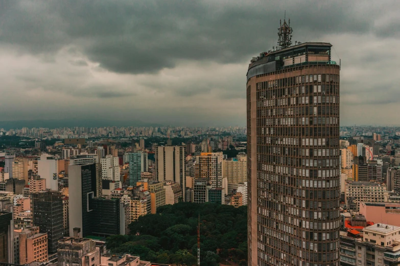 a tall building sitting in the middle of a city, inspired by Elsa Bleda, pexels contest winner, brutalism, brazil, cloudy weather, panorama, journalism photo