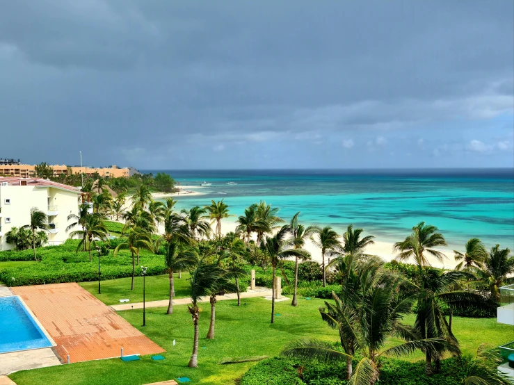 a view of a beach with palm trees and a swimming pool, while it's raining, varadero beach, view of sea, mar-a-lago