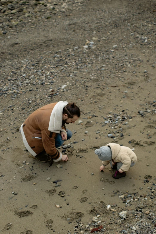 a woman and a child playing in the sand, inspired by Vija Celmins, unsplash, gravel and scree ground, alaska, seaview, 2010s