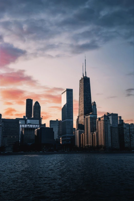 a large body of water with a city in the background, by Jacob Burck, pexels contest winner, chicago skyline, sunset photo, tall structures, towers