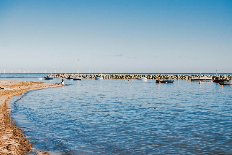 a group of boats sitting on top of a body of water, by Rachel Reckitt, unsplash, australian beach, near a jetty, gadigal, on a bright day