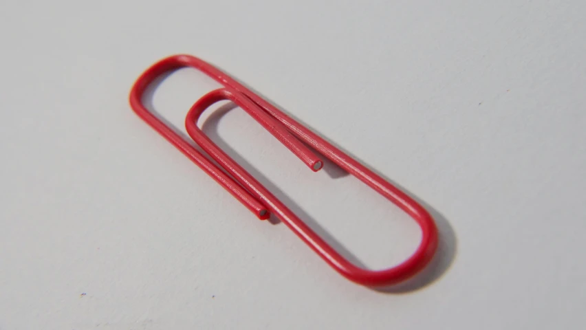 a red paper clip on a white surface, by Julian Allen, flickr, plasticien, ultra realistic, 105mm, rpg item, steel