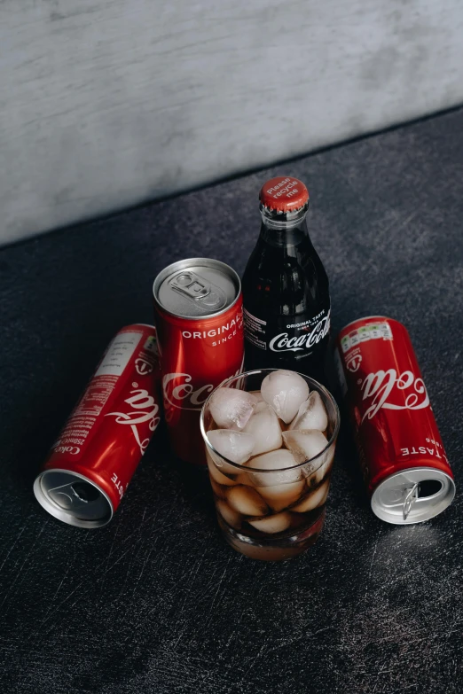 a group of soda cans sitting on top of a table, inspired by Dorothy Coke, pexels contest winner, hyperrealism, black and red, drink, silver light, chicago