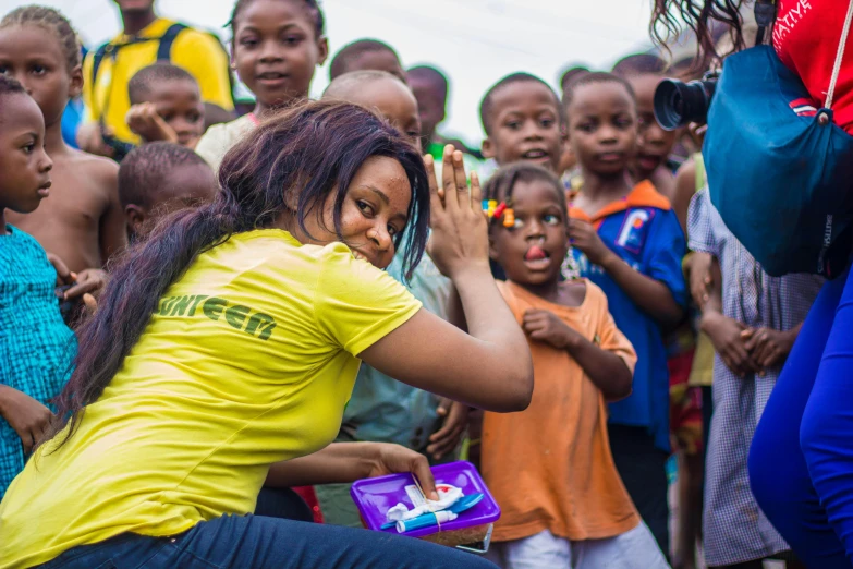 a woman dancing in front of a crowd of children, by Daniel Lieske, pexels contest winner, yellow and green scheme, giving gifts to people, makeup, township