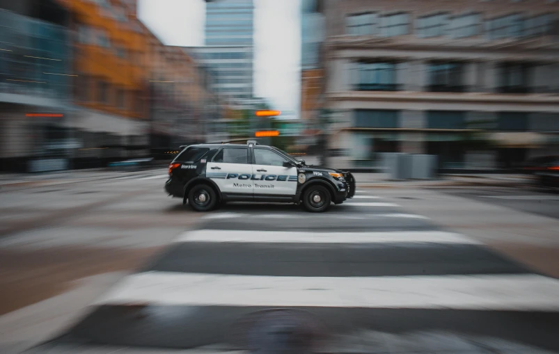 a police car driving down a city street, pexels contest winner, photorealism, minneapolis, 15081959 21121991 01012000 4k, plain background, people at work