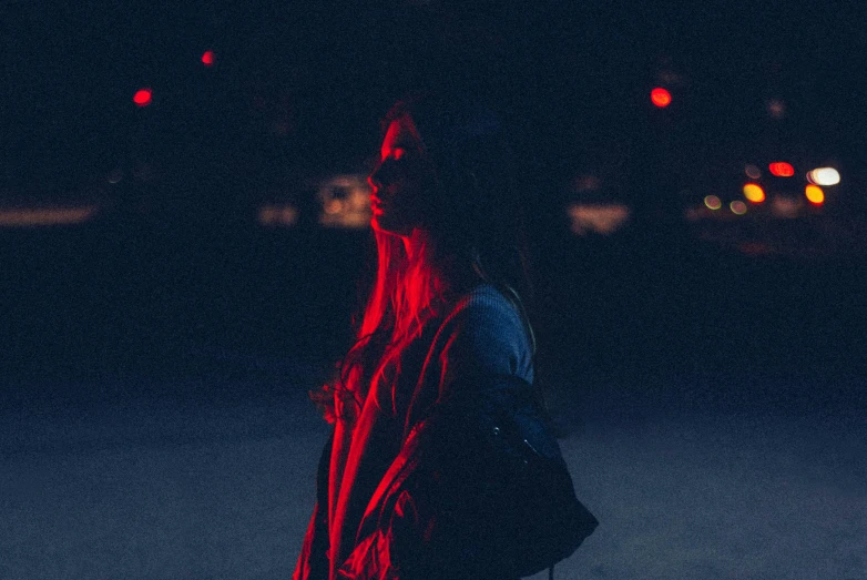 a woman standing in the middle of a street at night, inspired by Elsa Bleda, pexels contest winner, dark blue and red, teenage girl, profile pic, red