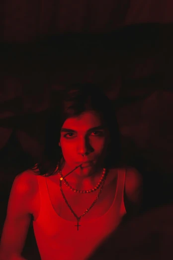 a woman sitting in a chair with a cigarette in her mouth, an album cover, inspired by Elsa Bleda, unsplash, small red lights, soft devil queen madison beer, grainy movie still, amelie poulain
