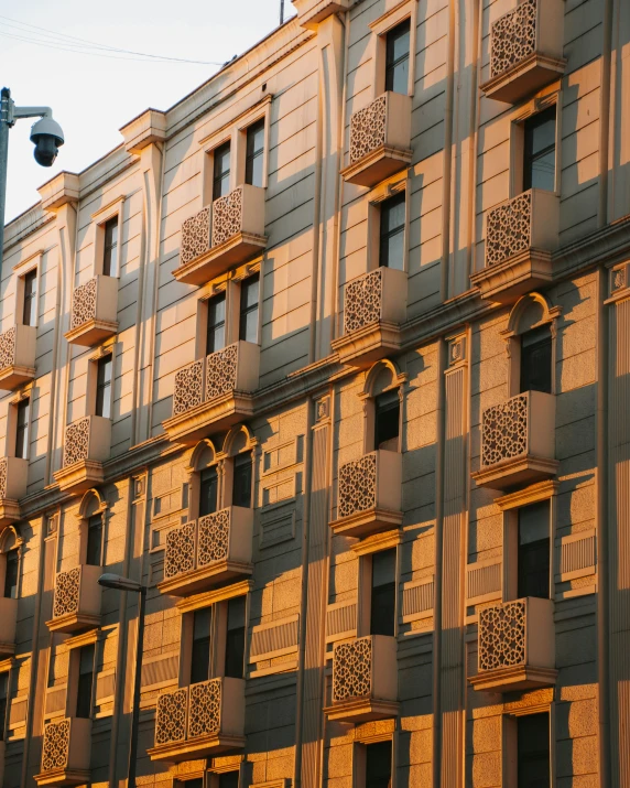 a very tall building with many windows and balconies, inspired by Ricardo Bofill, pexels contest winner, art nouveau, evening sunlight, palermo city street, hotel room, soft golden light