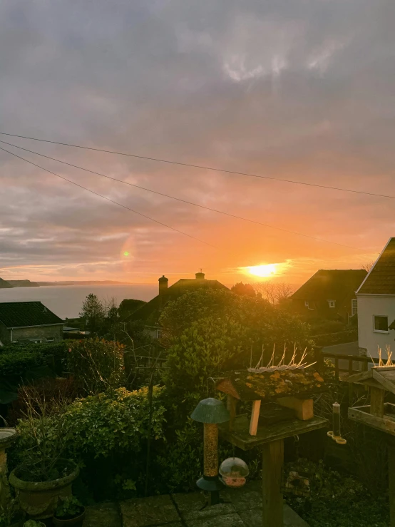 a house sitting on top of a lush green hillside, a picture, happening, sunset and big clouds behind her, holywood scene, taken from the high street, views to the ocean