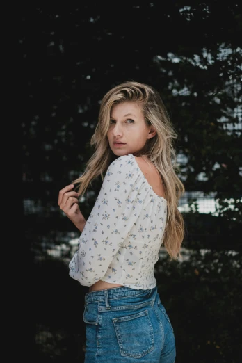 a woman standing in front of a tree, trending on pexels, renaissance, blonde long hair, wearing a shirt and a jean, profile image, floral clothes