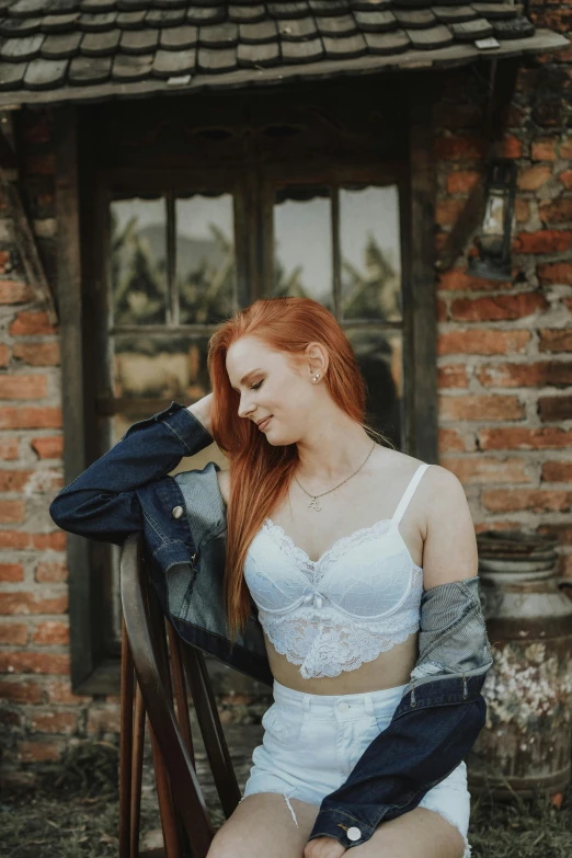 a woman sitting on a chair in front of a brick building, a picture, inspired by Elsa Bleda, unsplash contest winner, renaissance, posing together in bra, cute young redhead girl, white bra, profile image