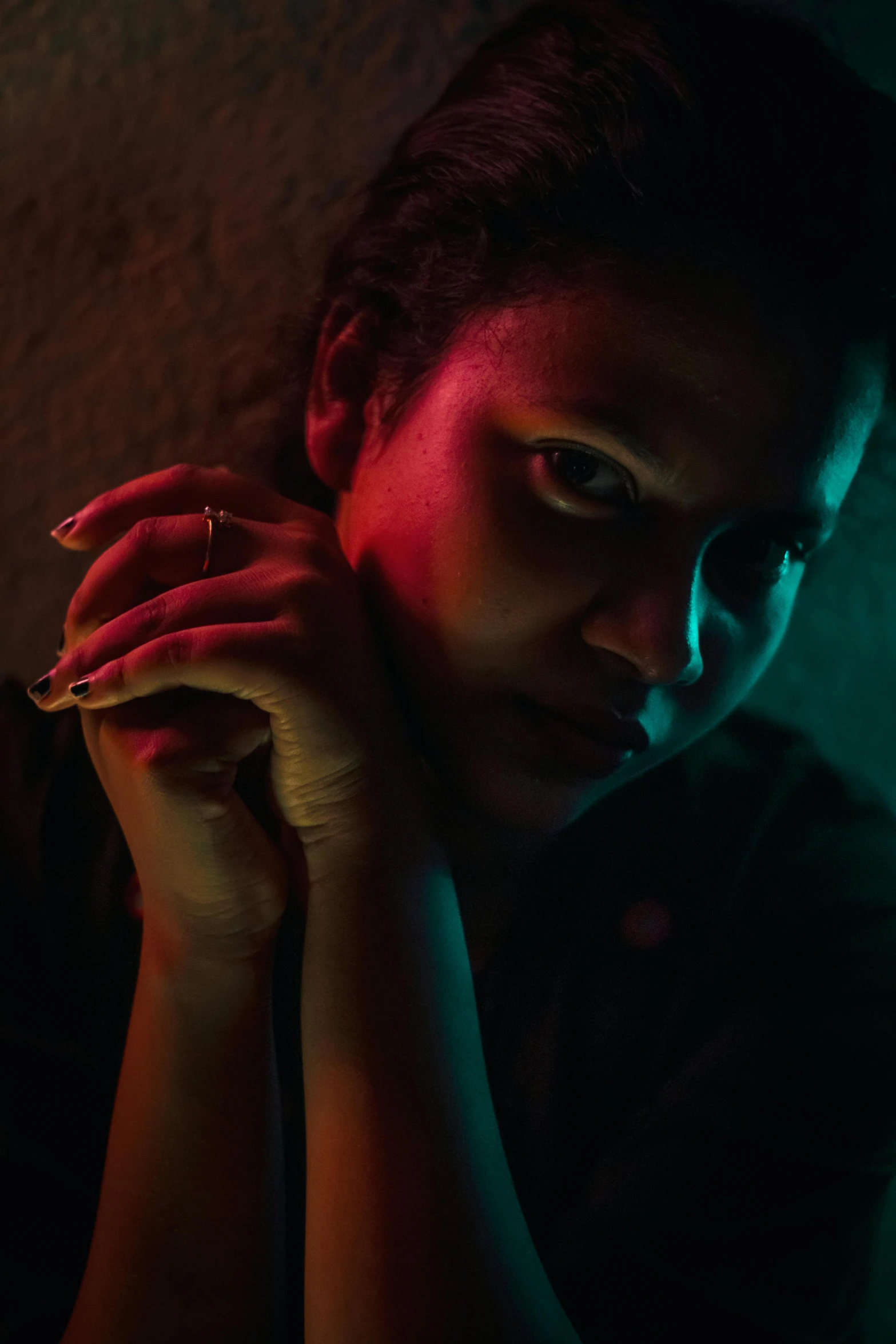 a woman holding a microphone in a dark room, inspired by Nan Goldin, renaissance, dark complexion, pensive, photo of a hand jewellery model, looking serious