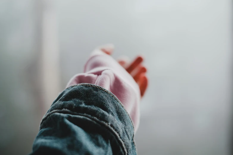 a person holding their hand out in front of a window, by Emma Andijewska, trending on pexels, wearing a pink hoodie, wearing jeans, haze over the shoulder shot, bandage on arms