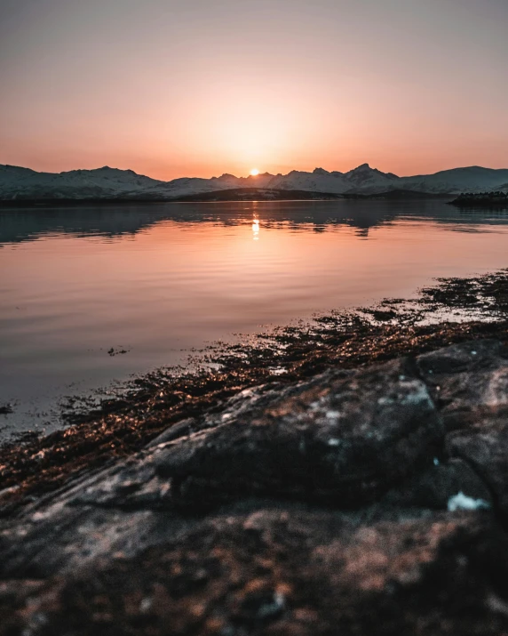 the sun is setting over a body of water, by Sebastian Spreng, pexels contest winner, mountains in the background, hamar, high quality image”, intense details