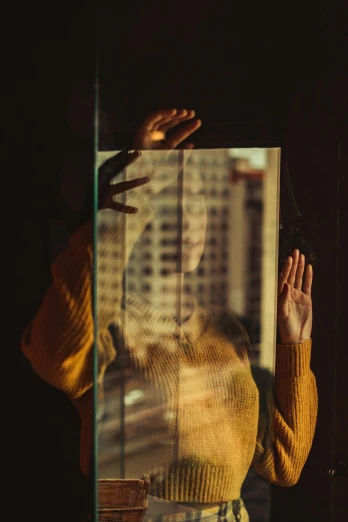 a woman standing in front of a window with her hands in the air, inspired by Elsa Bleda, realism, on a reflective gold plate, alessio albi, transparent glass woman, cityscape
