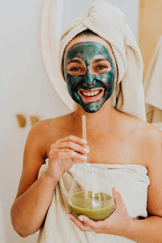 a woman with a towel wrapped around her head drinking a green smoothie, trending on pexels, renaissance, smiling mask, face painting, foil, blue